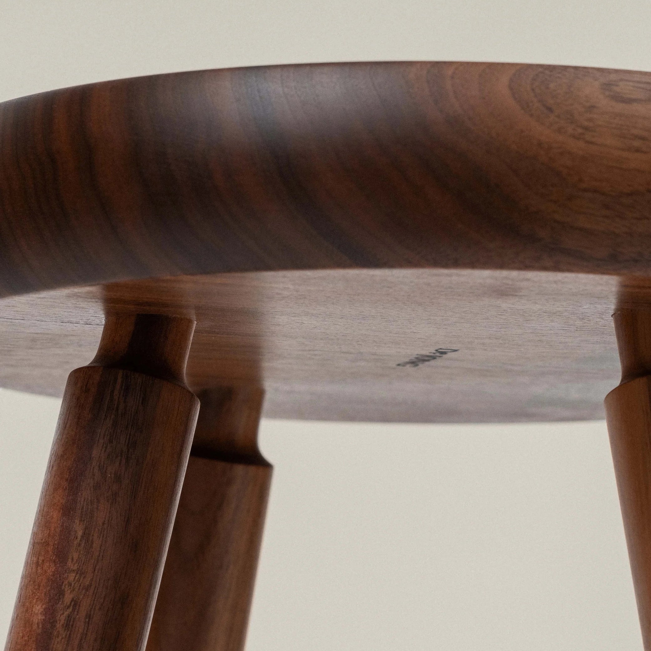 Close-up of a walnut wooden stool with a plain background