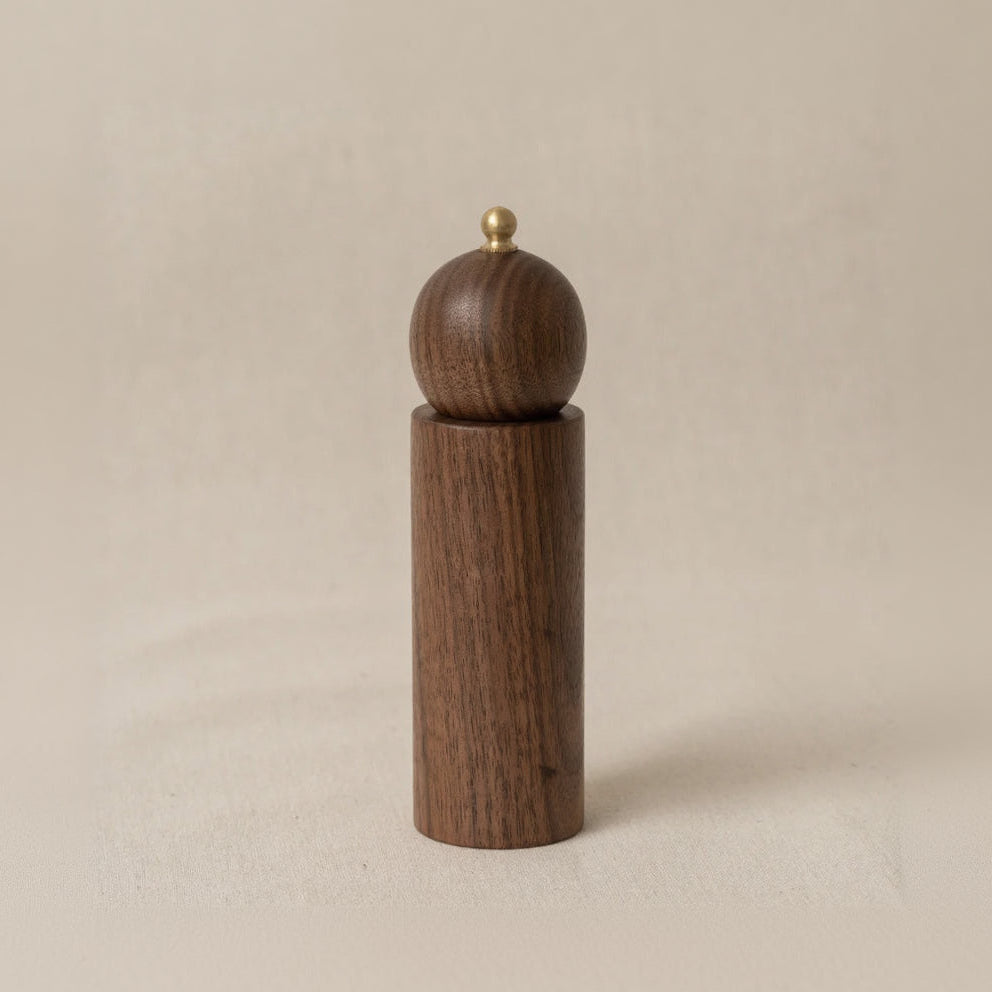 Wooden pepper grinder on a beige background