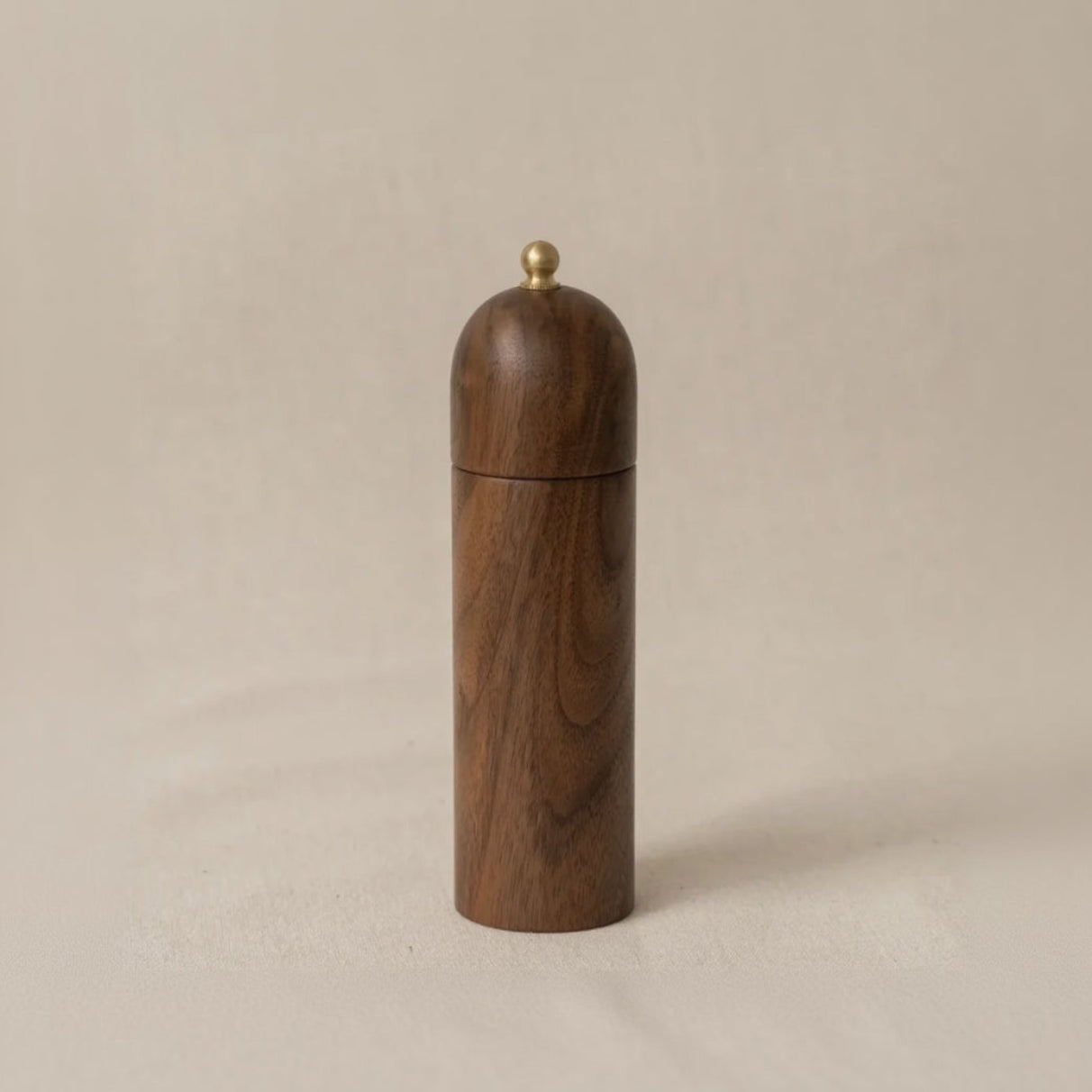 Wooden walnut pepper grinder on a beige background