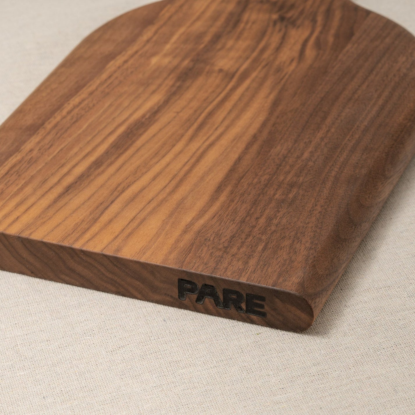 Wooden cutting board with 'PARE' branding on a beige background